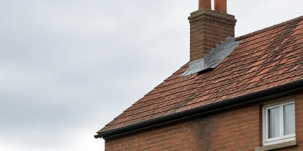 Worn lead flashing around a chimney on a tiled UK roof